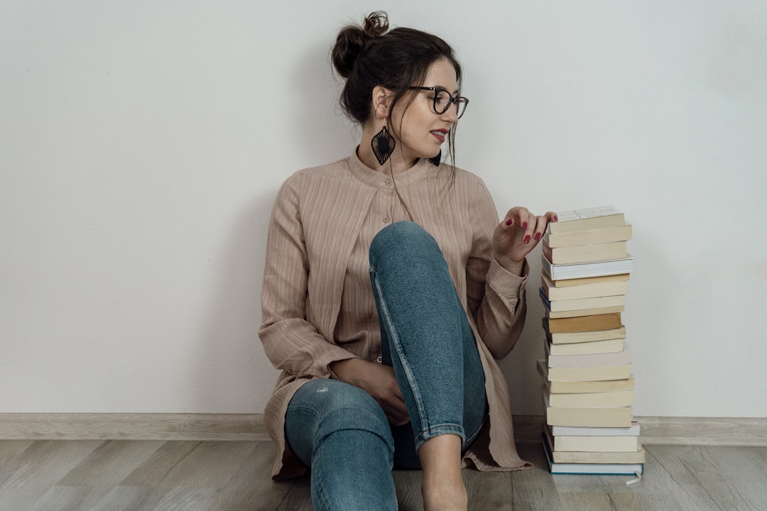 a woman sitting on the floor with a stack of books