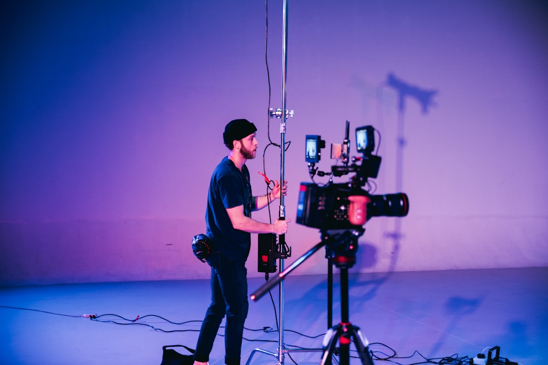 man in blue dress shirt and black pants standing on black microphone